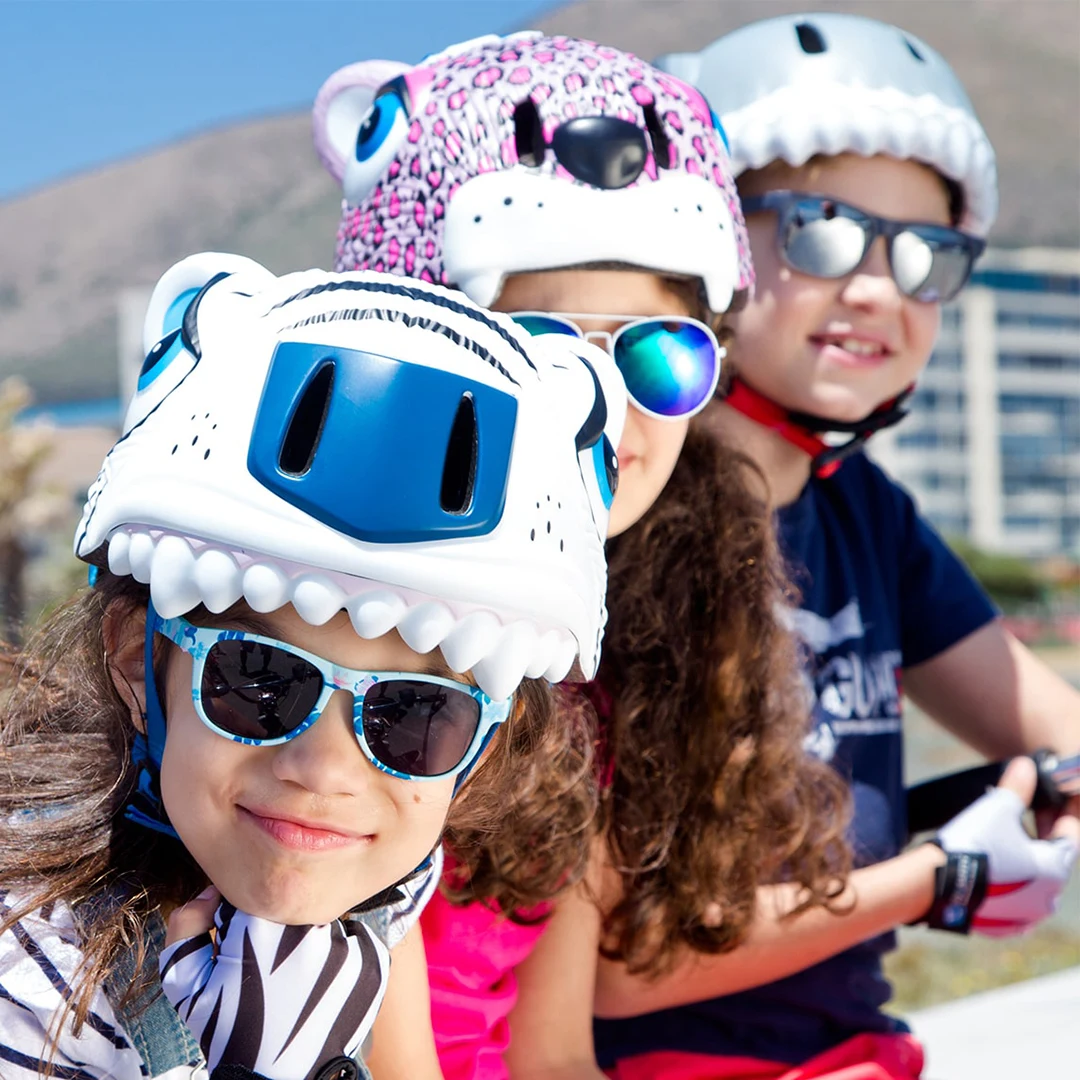 Three children wearing Crazy Safety's animal-shaped bike helmets