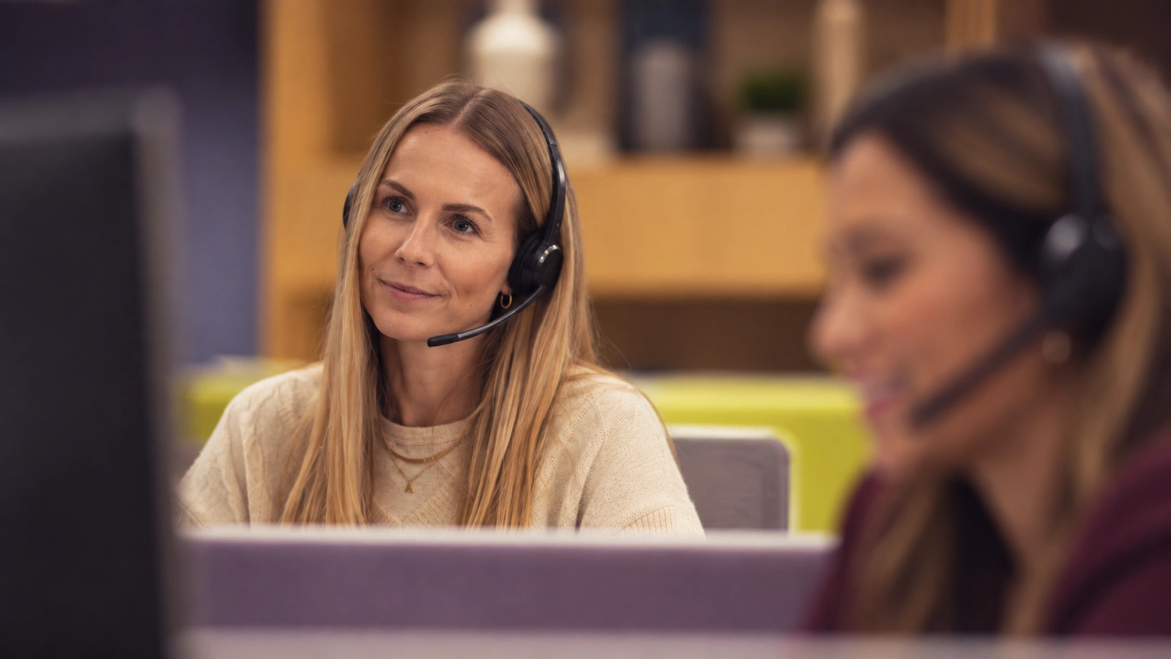 A woman with a headset smiles at her desk