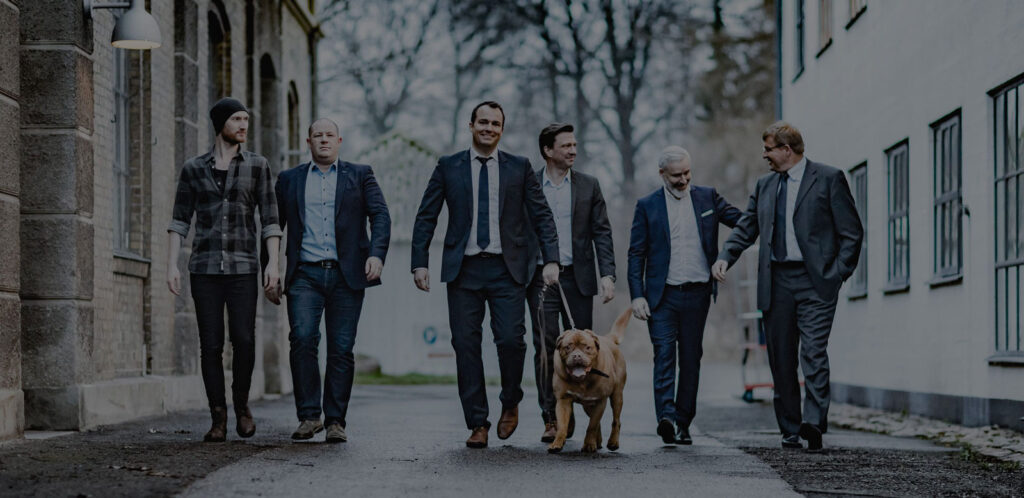 Seks personer i jakkesæt og en hund.