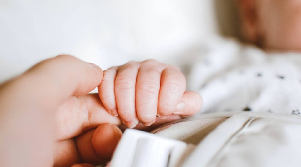 Person der holder en babys hånd.