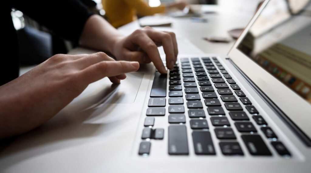 Hænder der skriver på en bærbar computer.